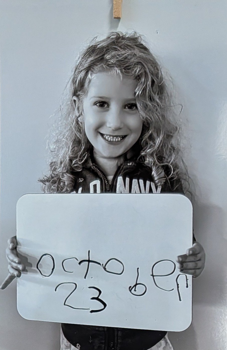 Isla, the birthday girl, holding a sign with her birthday — October 23